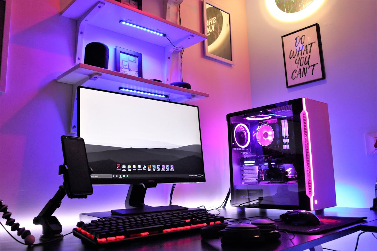 A sleek gaming setup featuring RGB lighting with a desktop, monitor, and smartphone in a vibrant room.